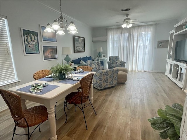 50 Forney Johnston Dr Unit 7A, Dauphin Island, AL 36528 - dining area featuring visible vents, a wall unit AC, ornamental molding, ceiling fan with notable chandelier, and wood finished floors