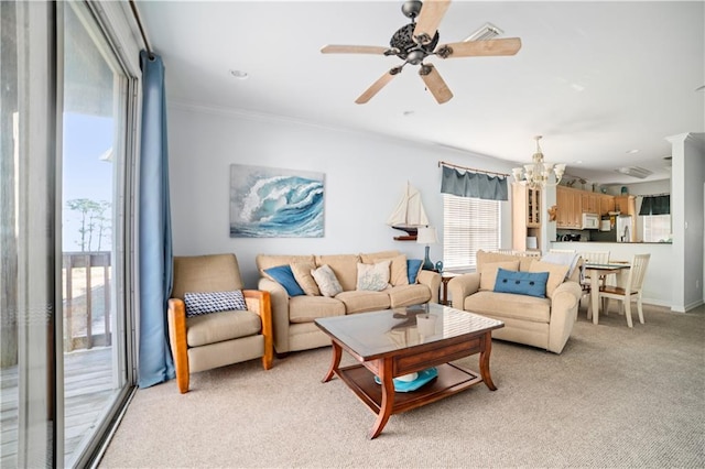 living room with ceiling fan with notable chandelier, light colored carpet, and ornamental molding