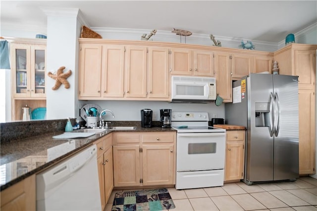 kitchen with light tile patterned floors, white appliances, dark stone counters, ornamental molding, and sink