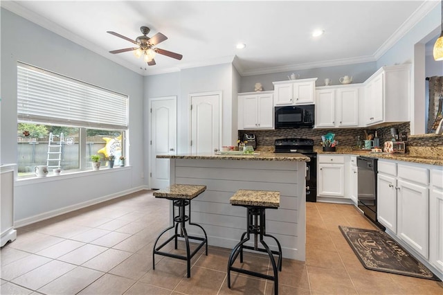 kitchen with light tile patterned floors, a center island, light stone countertops, black appliances, and white cabinets