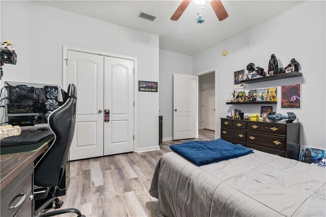 bedroom with light wood-type flooring, ceiling fan, and a closet