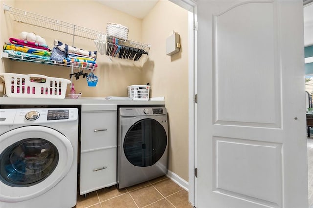 laundry area with washer and clothes dryer and light tile patterned floors