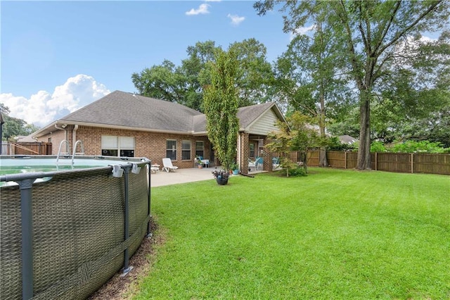 rear view of house with a fenced in pool, a yard, and a patio area