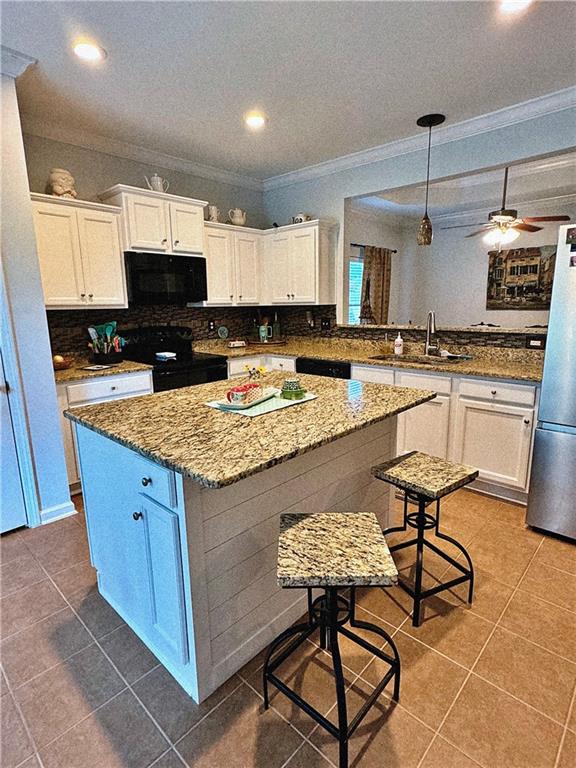 kitchen with range, a center island, crown molding, and ceiling fan