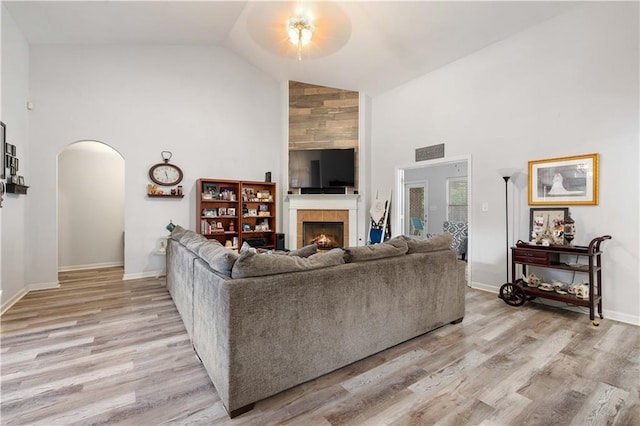 living room featuring ceiling fan, a fireplace, high vaulted ceiling, and light hardwood / wood-style flooring