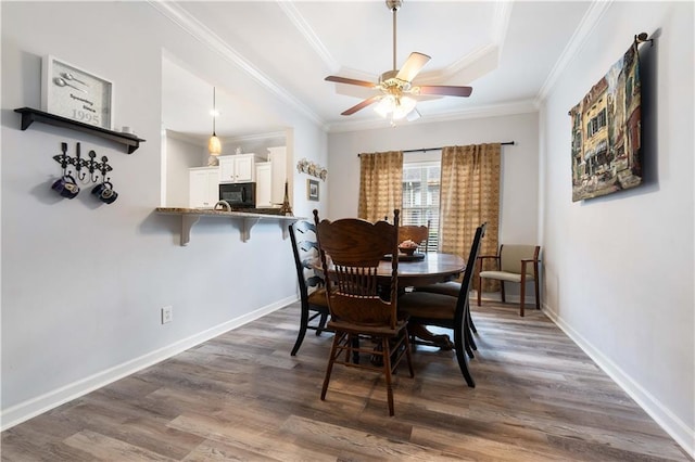 dining room with ornamental molding, dark hardwood / wood-style floors, and a raised ceiling