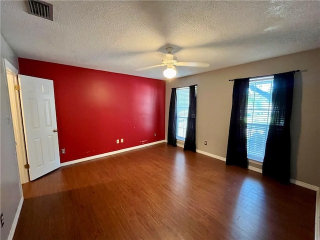 empty room with a textured ceiling, dark hardwood / wood-style floors, and ceiling fan