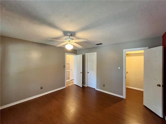 unfurnished bedroom with a textured ceiling, dark hardwood / wood-style floors, and ceiling fan