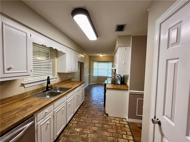 kitchen featuring stainless steel dishwasher, white cabinetry, butcher block counters, and sink