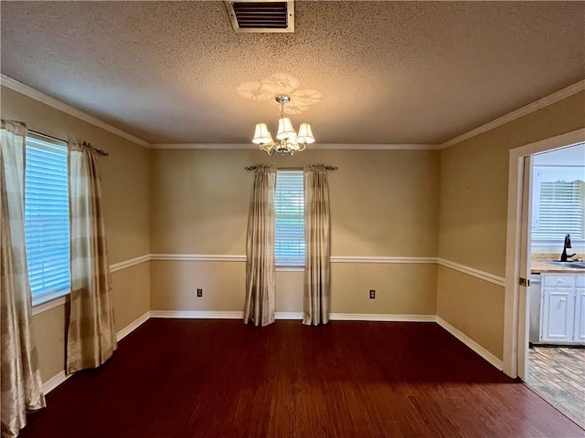 unfurnished dining area featuring dark wood-type flooring, a textured ceiling, crown molding, sink, and a notable chandelier