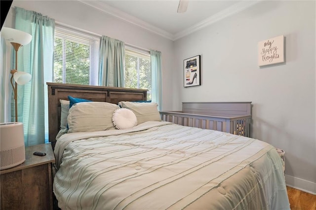 bedroom featuring baseboards, a ceiling fan, wood finished floors, and ornamental molding