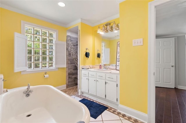 bathroom with a freestanding bath, baseboards, ornamental molding, and vanity