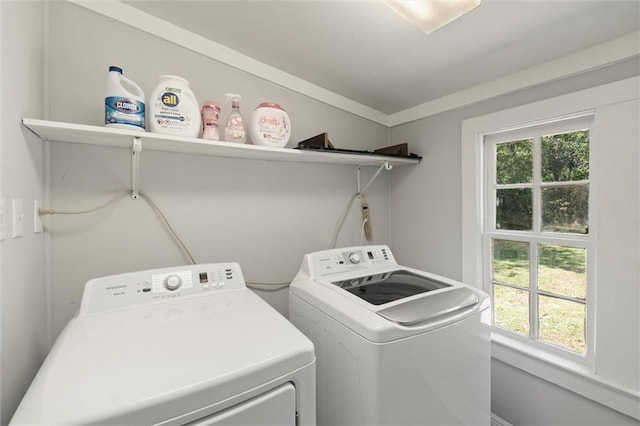 clothes washing area featuring washing machine and dryer, a wealth of natural light, and laundry area