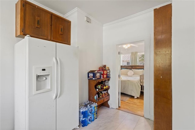interior space with brown cabinetry, white refrigerator with ice dispenser, a ceiling fan, and crown molding