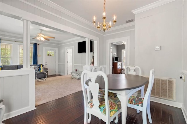 dining space featuring dark wood finished floors, visible vents, crown molding, and ceiling fan with notable chandelier