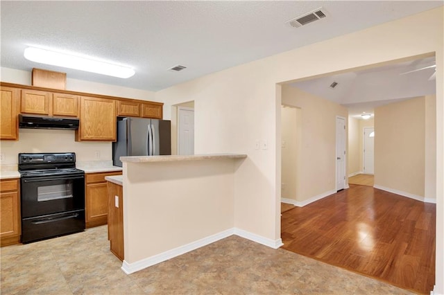 kitchen featuring light hardwood / wood-style flooring, stainless steel fridge, and black / electric stove