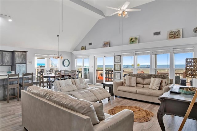 living area featuring visible vents, ceiling fan with notable chandelier, high vaulted ceiling, and light wood-style flooring