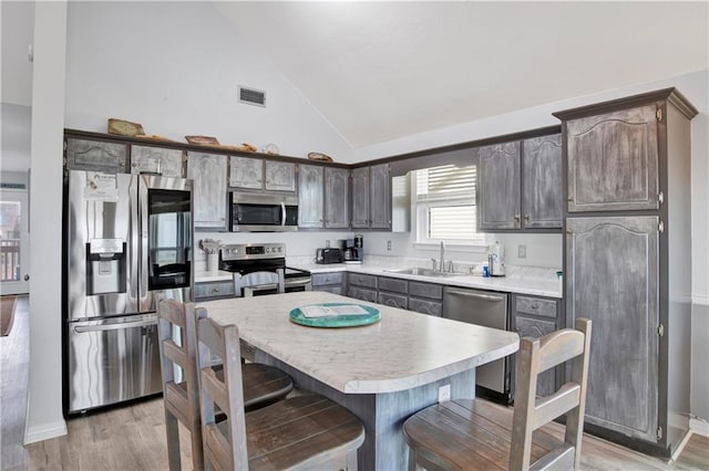 kitchen with visible vents, a breakfast bar area, light countertops, appliances with stainless steel finishes, and a sink