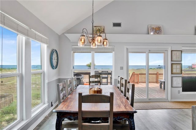 dining area featuring a notable chandelier, visible vents, high vaulted ceiling, and wood finished floors