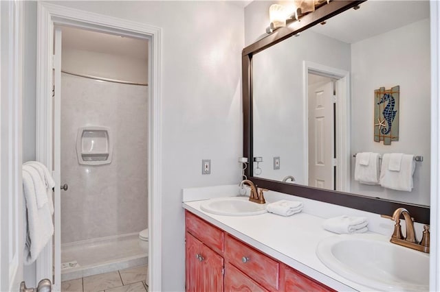 bathroom with double vanity, a stall shower, toilet, and a sink