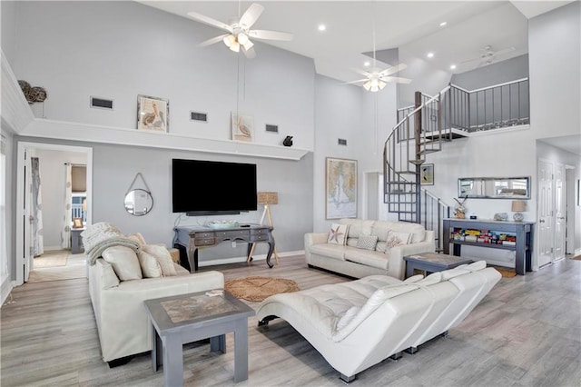 living room with wood finished floors, stairway, a ceiling fan, and visible vents