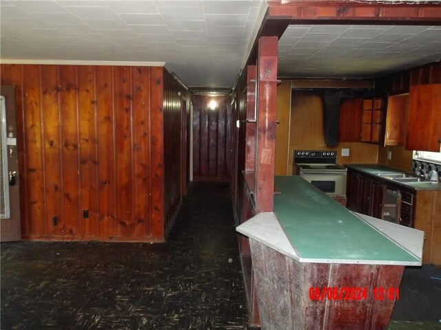 kitchen featuring sink, white electric range oven, and wooden walls