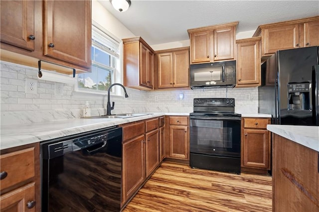 kitchen with sink, decorative backsplash, light hardwood / wood-style floors, and black appliances