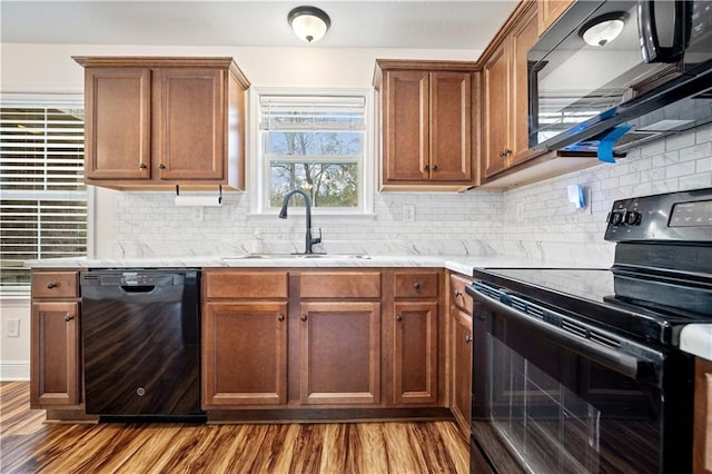 kitchen with hardwood / wood-style floors, decorative backsplash, black appliances, and sink