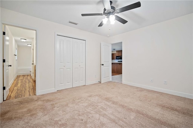 unfurnished bedroom featuring ceiling fan, light colored carpet, and a closet