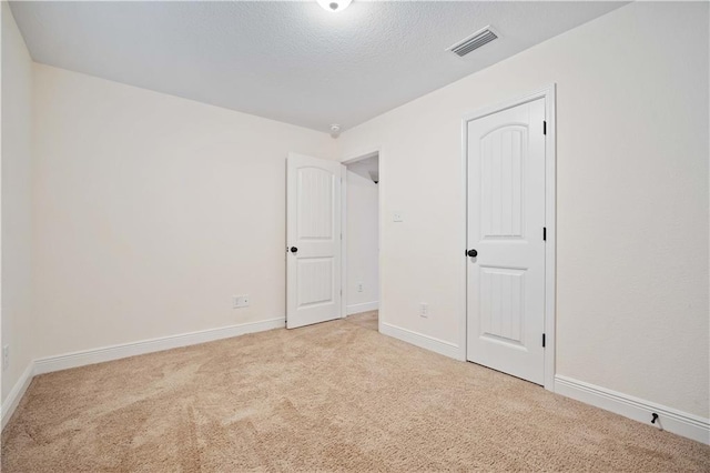 spare room with light colored carpet and a textured ceiling