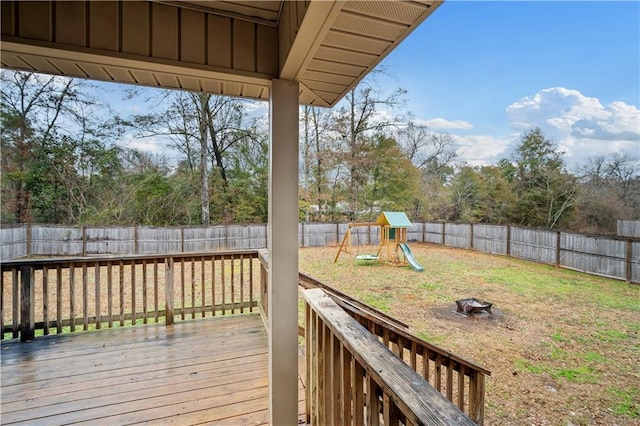 wooden terrace featuring a playground, a fire pit, and a lawn