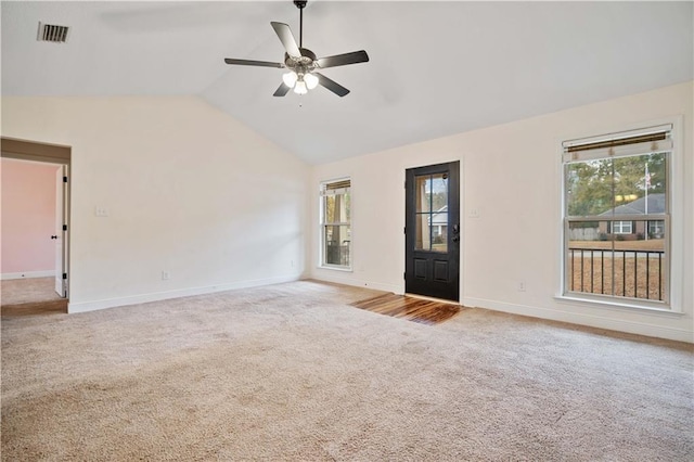 unfurnished living room with ceiling fan, plenty of natural light, vaulted ceiling, and carpet