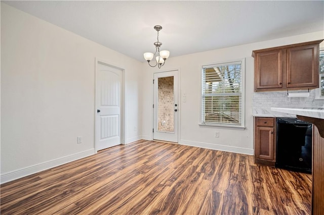 kitchen featuring dark wood-type flooring, tasteful backsplash, a chandelier, dishwasher, and pendant lighting