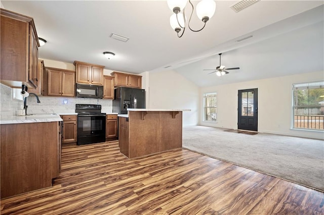 kitchen with lofted ceiling, sink, tasteful backsplash, a center island, and black appliances