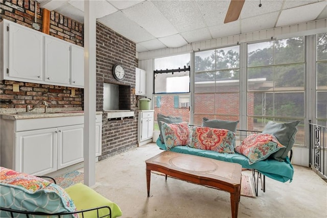 interior space with ceiling fan, a wealth of natural light, sink, and a drop ceiling