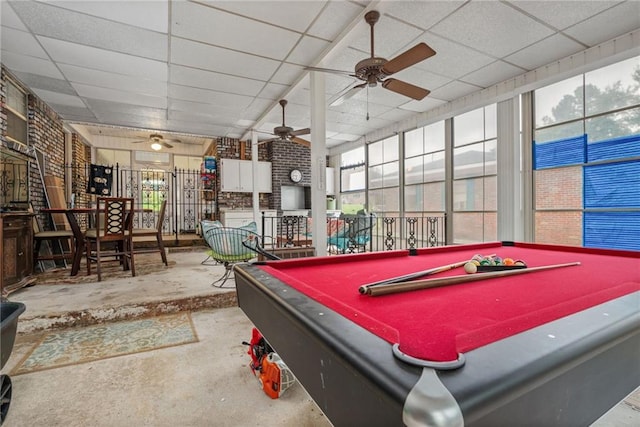 recreation room with a drop ceiling, concrete flooring, and ceiling fan