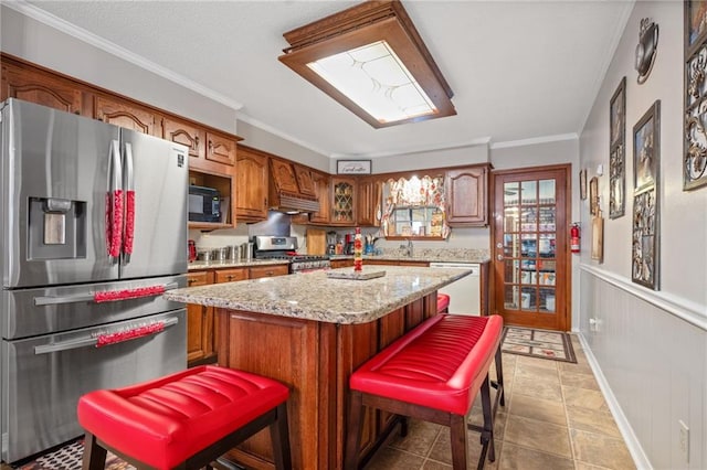 kitchen with a kitchen bar, light tile patterned floors, ornamental molding, a kitchen island, and stainless steel appliances