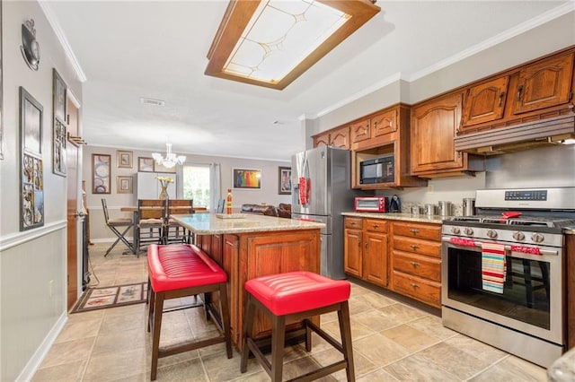 kitchen featuring crown molding, an inviting chandelier, a kitchen island, stainless steel appliances, and light stone countertops