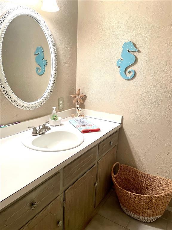 bathroom featuring a textured wall, tile patterned flooring, and vanity