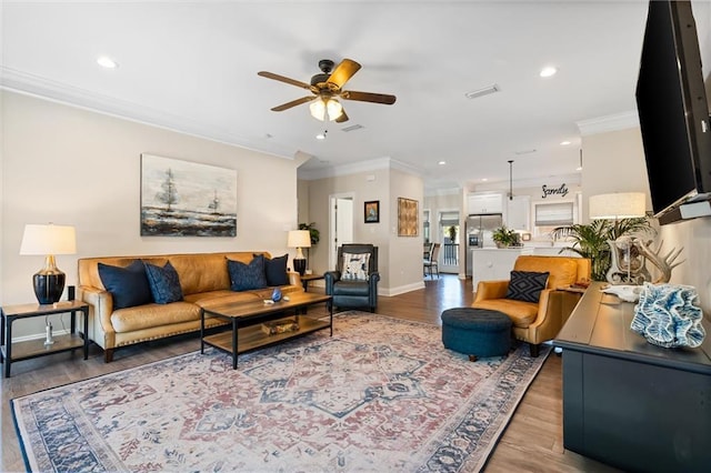 living area with baseboards, visible vents, ornamental molding, wood finished floors, and recessed lighting