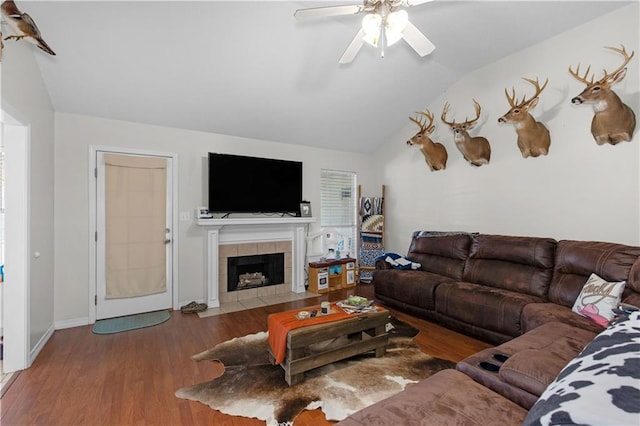 living area with a fireplace, lofted ceiling, a ceiling fan, wood finished floors, and baseboards