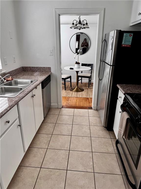 kitchen featuring white cabinets, sink, black electric range, stainless steel dishwasher, and light hardwood / wood-style flooring