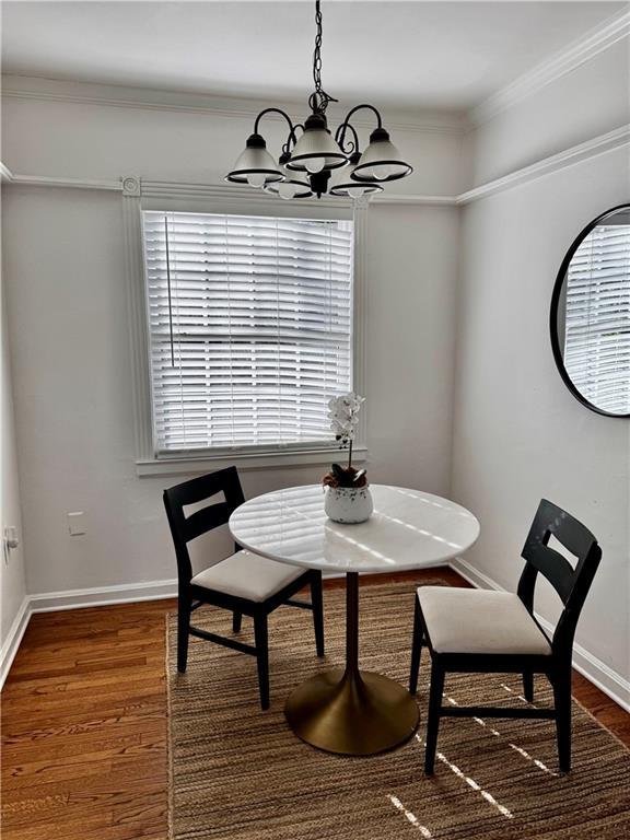 dining room with a wealth of natural light, crown molding, a chandelier, and dark hardwood / wood-style floors