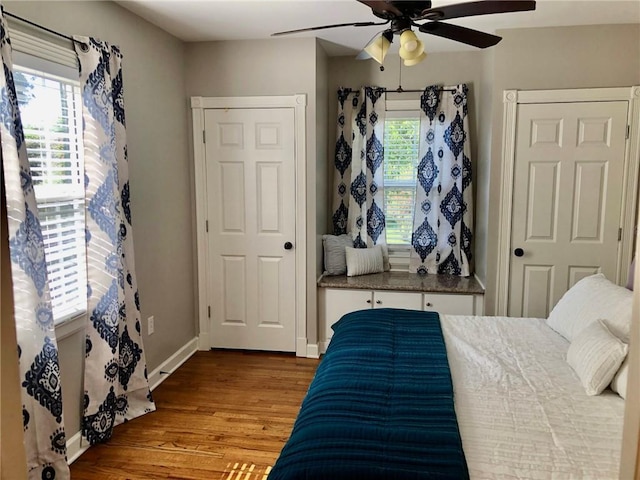 bedroom featuring ceiling fan, wood-type flooring, and multiple windows