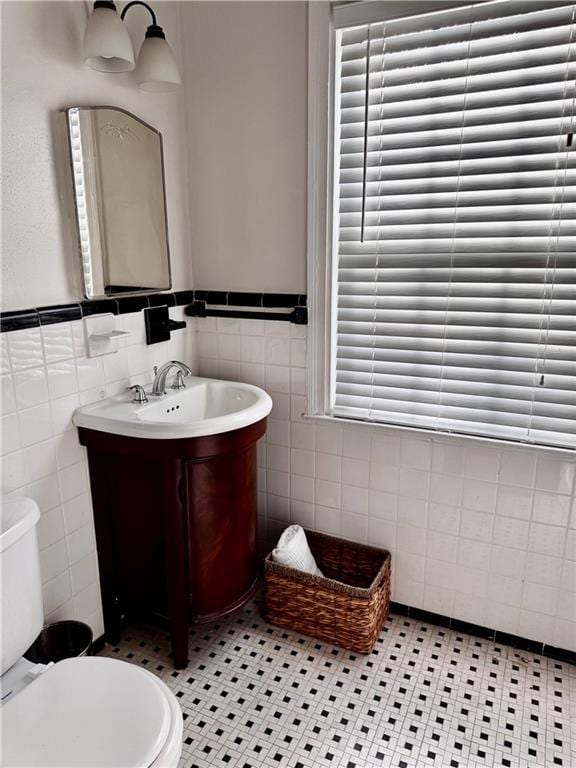 bathroom featuring tile patterned floors, vanity, tile walls, and toilet