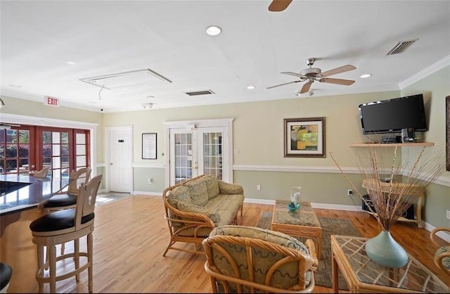 living room featuring french doors, light hardwood / wood-style flooring, ceiling fan, and crown molding