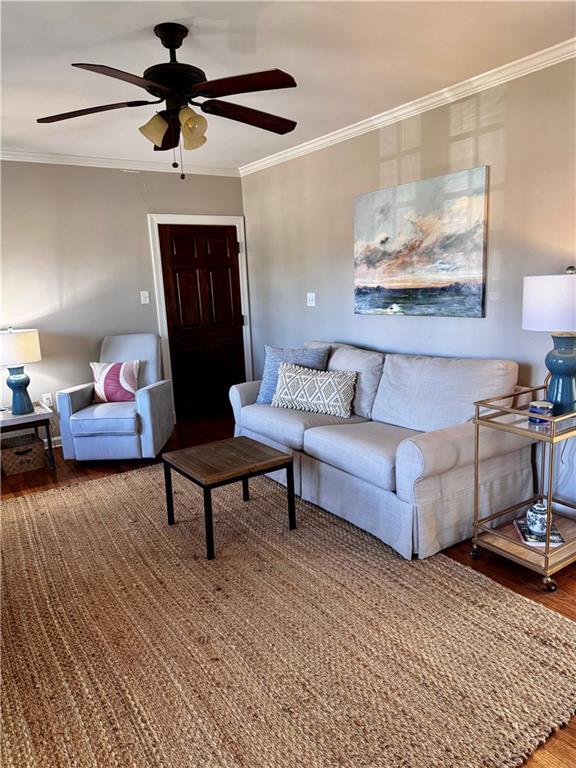 living room featuring hardwood / wood-style floors, ceiling fan, and crown molding