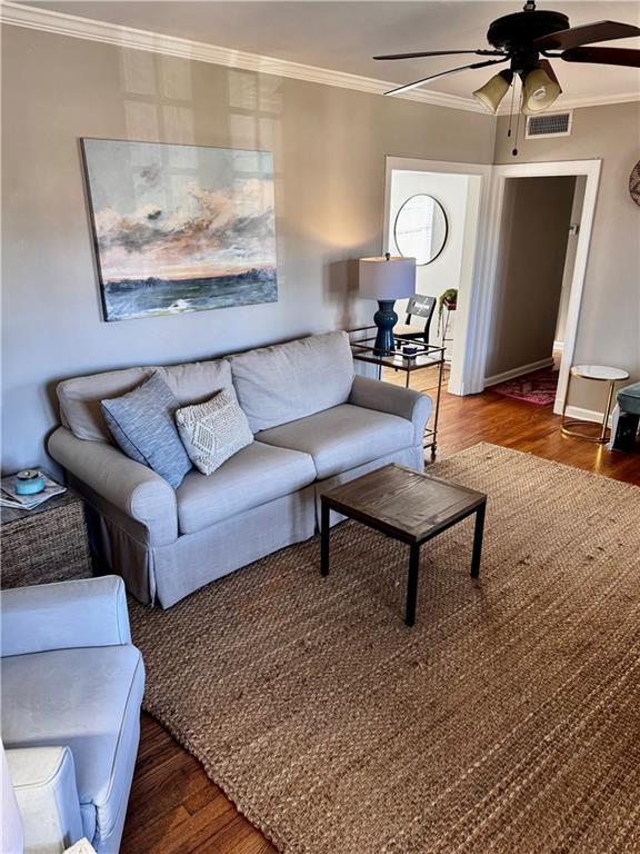 living room featuring ceiling fan, crown molding, and dark wood-type flooring