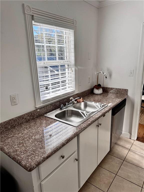 kitchen featuring sink, white cabinets, stainless steel dishwasher, light tile patterned flooring, and ornamental molding