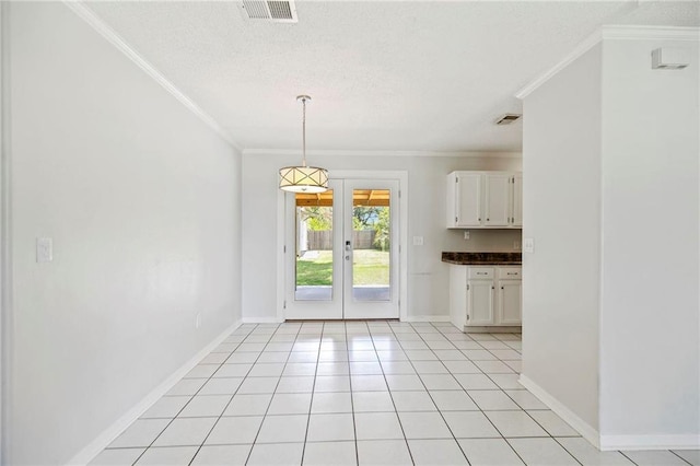 unfurnished dining area with light tile patterned floors, ornamental molding, french doors, and a textured ceiling